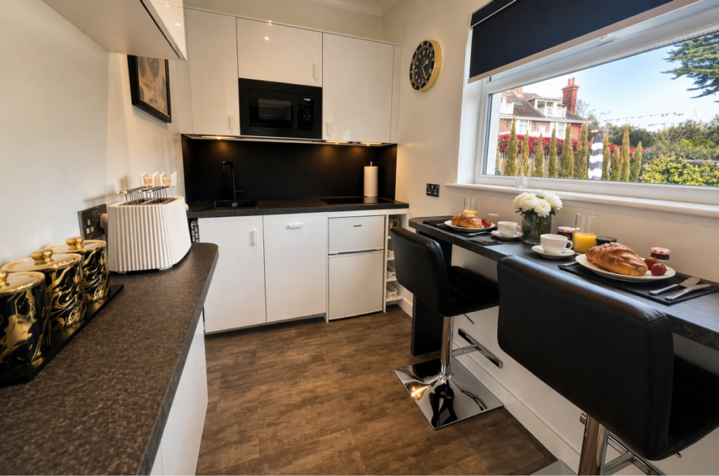 Modern kitchenette with breakfast bar, croissants and coffee, bright window view in luxury Bournemouth B&B